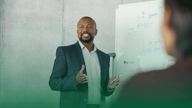 Homem apresentando conteúdo em um quadro branco durante um treinamento corporativo.