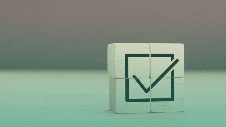 Cubo de madeira com símbolo de checklist marcado, representando conformidade e validação de processos em um contexto corporativo.