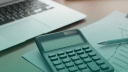 Notebook e calculadora sobre uma mesa de trabalho, representando controle financeiro, gestão de riscos e estruturação de processos de compliance.